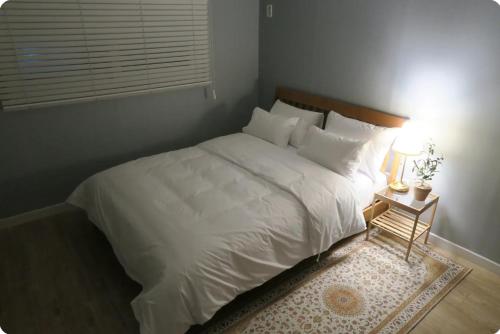 a bedroom with a large white bed and a table with a lamp at Gaon guesthouse in Jeonju