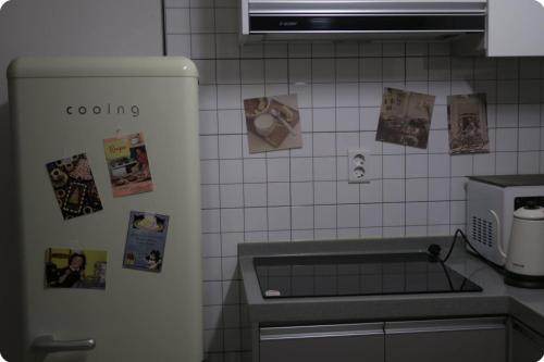 a kitchen with a refrigerator with pictures on the wall at Gaon guesthouse in Jeonju