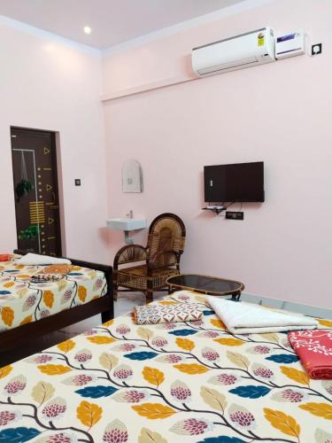 a room with two beds and a flat screen tv at Mayurah Illam in Kanyakumari