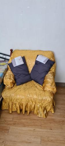 a yellow couch with two pillows on top of it at Cambridge Village 