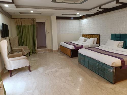 una habitación de hotel con 2 camas y una silla en GK Residency Kailash Colony en Nueva Delhi