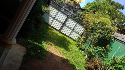 a green yard with a fence and some plants at VA Villa Hikkaduwa in Hikkaduwa