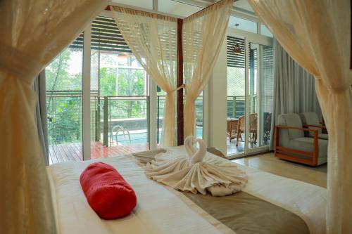a bedroom with a bed with two red pillows on it at Kuruva Island Resort And Spa - By KABINI BREEZE in Mananthavady