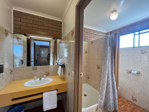 a bathroom with a sink and a tub at Eaglehawk Motel Bendigo in Bendigo