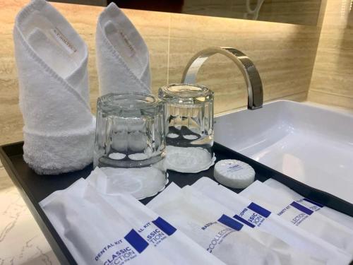 a bathroom sink with a glass jar and towels at ST Hotel Wattay Airport in Vientiane