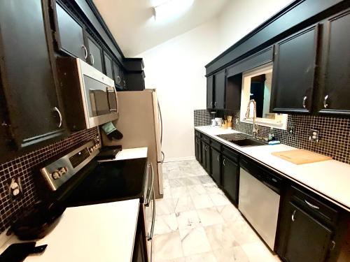 a kitchen with black cabinets and a sink at Elegant Parisian Home near Fondren in Jackson