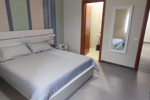 um quarto com uma cama branca e um espelho em Civico 4 em Campagnano di Roma