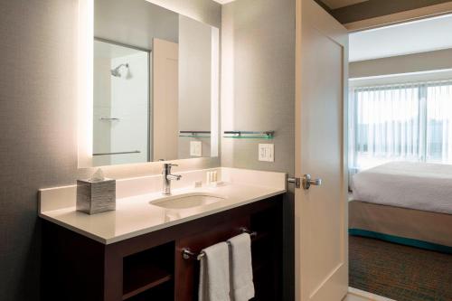 a bathroom with a sink with a mirror and a bed at Residence Inn by Marriott Boston Burlington in Burlington