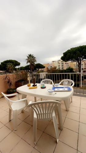 une table blanche et des chaises assises sur une terrasse dans l'établissement La terrasse de Gruissan, à Gruissan