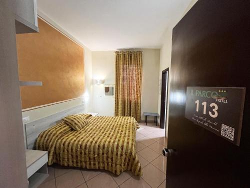 グロッセートにあるHotel Il Parcoのベッドとドアに時計が付いたホテルルームです。