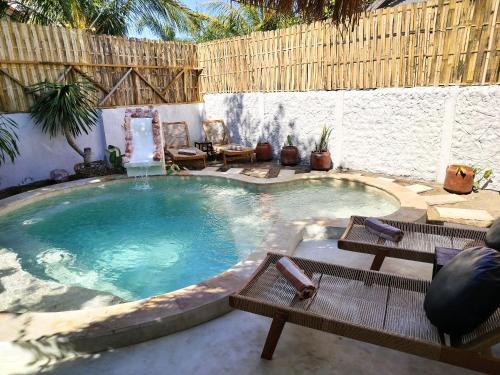 a large swimming pool with two benches and a table at Amel House in Gili Islands