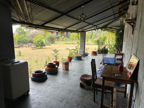 a patio with a table and chairs and plants at Dreamwoods A travellers farm in Dharamshala
