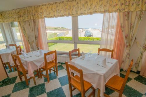 a dining room with two tables and a large window at Hotel Costa de Ajo in Ajo