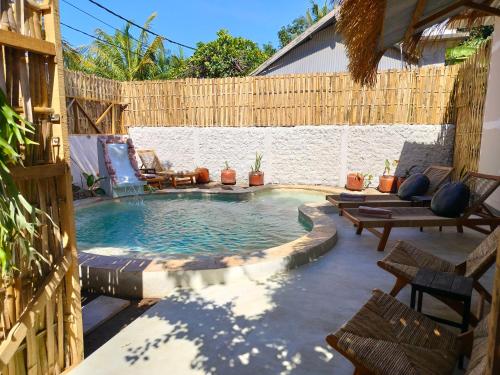 a swimming pool in a backyard with a wooden fence at Amel House in Gili Air