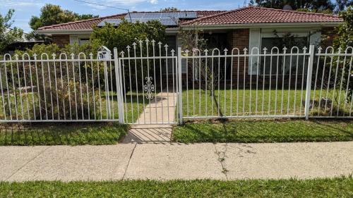 a white fence in front of a house at BIDWILL GARDENS ON MIDDLETON - 2 Rooms A Private Room with a King-Size Bed or Open Lounge Room Floor Mattress SHARED Bathroom FREE Kitchen Essentials FREE Laundry Facilities Fast NBN WIFI HDTV NETFLIX, YOUTUBE, KAYO Meal and Transport Service Available in Bidwill