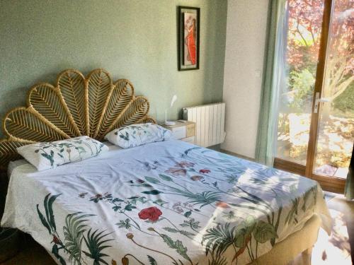 a bedroom with a large bed with a floral bedspread at La fabrique des petits bonheurs in Dieulefit