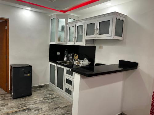a kitchen with white cabinets and a black counter top at Acogedor y moderno Spot para parejas! in Pantoja