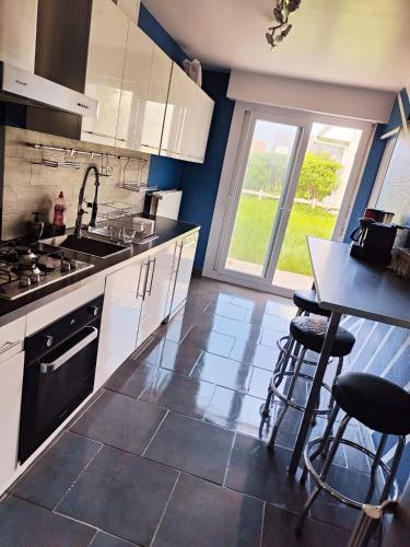 - une cuisine avec des placards blancs, un évier et une table dans l'établissement La Portel'Heurt, à Le Portel