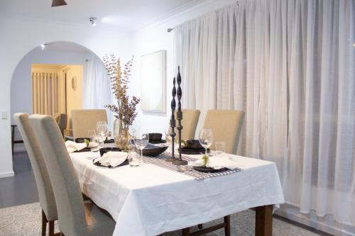 a dining room table with a white table cloth and chairs at Cozy Cottage for Families, Sleeps 8 , Big backyard, parking for 4 cars, Walking distance to Shopping mall in Ballarat