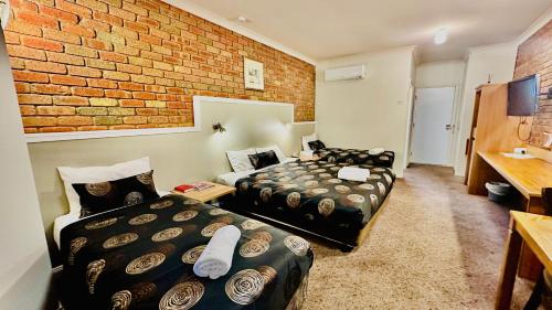 a room with two beds and a brick wall at Early Australian Motor Inn in Mildura
