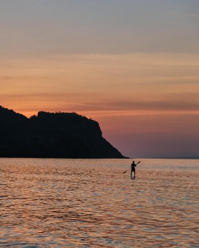 a person standing in the water at sunset at Myamo Beach Lodge in Jereweh