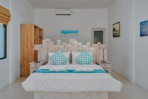 a bedroom with a large bed with blue and white pillows at Myamo Beach Lodge in Jereweh