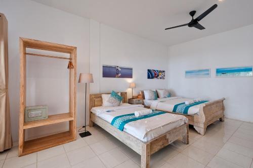 two beds in a room with a mirror and a fan at Myamo Beach Lodge in Jereweh