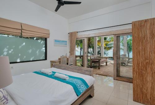 Myamo Beach Lodge في Jereweh: غرفة نوم بسرير وتلفزيون بشاشة مسطحة
