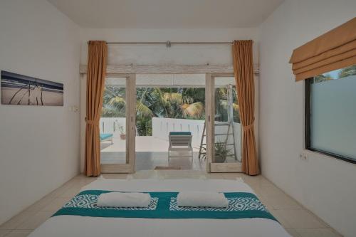 a bedroom with a bed and a view of a patio at Myamo Beach Lodge in Jereweh