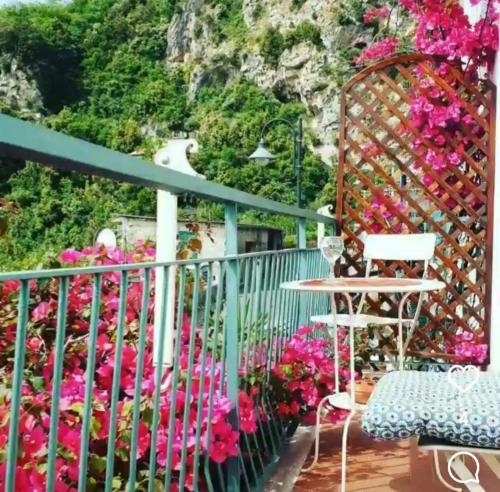 un balcón con flores, una mesa y una montaña en Amalfi Grace House - seaview, en Amalfi