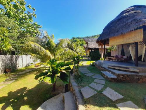 una casa con techo de paja y patio de césped en JEJU Cottages, en Kuta Lombok