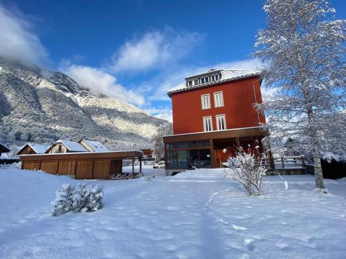 hôtel oberland في لو بورغ دوازو: مبنى احمر في الثلج مع جبال في الخلف