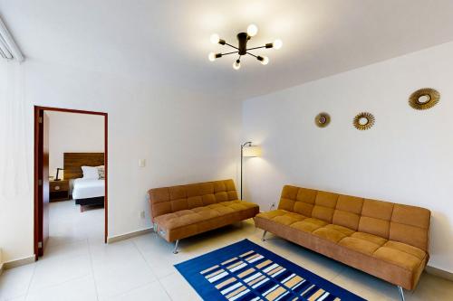 ein Wohnzimmer mit zwei braunen Sofas und einem Spiegel in der Unterkunft Cadetes 47 #302 in Mexiko-Stadt