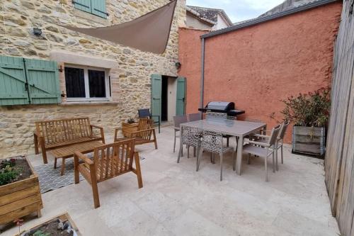 un patio avec une table, des chaises et un barbecue dans l'établissement Agréable maison de village avec piscine, à Saint-Hilaire-de-Brethmas