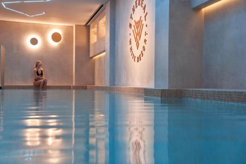 une femme assise à côté d'une piscine dans l'établissement Ethereal White Resort Hotel & Spa, à Héraklion