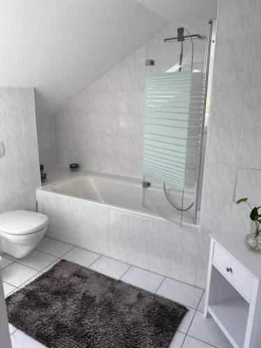 a white bathroom with a tub and a toilet at Am Kienbusch - Südliche Weinstraße - Dachgeschoss in Annweiler am Trifels