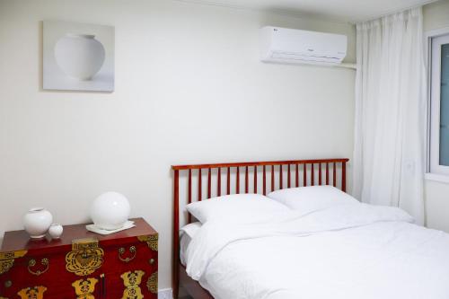 a bedroom with a bed with white sheets and a window at Stay Yeobaek,2BR,1BA - 2min to Hongdae, 5mins to Sangsu station in Seoul