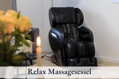 a black leather reclining chair next to a vase with a candle at Relax-Apartment-One Ravensburg in Ravensburg