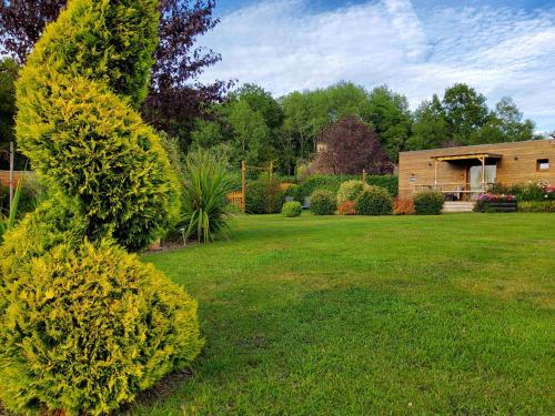une cour avec une maison et quelques buissons dans l'établissement L’’ Ensoleillée Au Doux Refuge, à Cordebugle