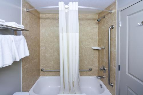 a bathroom with a tub and a shower with a shower curtain at Travelodge by Wyndham Kindersley in Kindersley