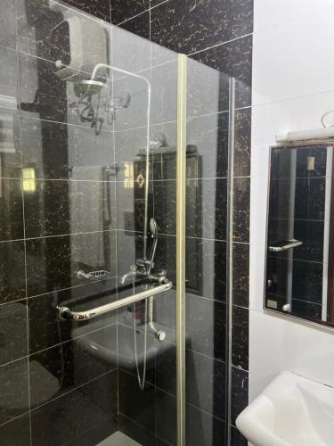 a black tiled bathroom with a shower and a sink at Victoria Homes - Lekki Apartment Lekki Phase 1 in Lekki