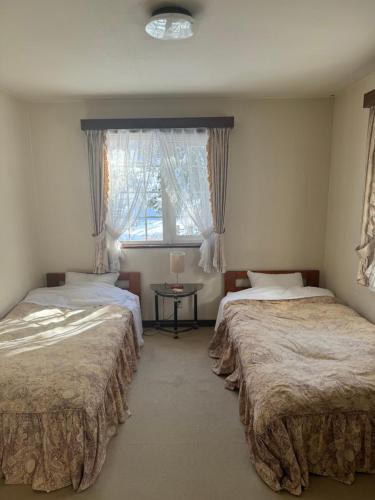 2 camas en una habitación con ventana y mesa en ALBERGO DEL PESCATORE en Minamiaizu