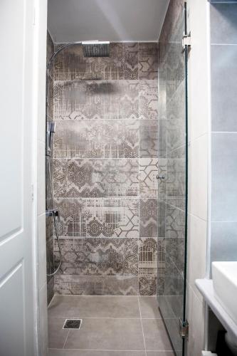 a bathroom with a shower with a tiled wall at Simo's Apartments in Egina