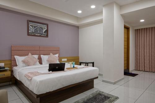a bedroom with a bed with a laptop on it at HOTEL AURELLIA in Sarkhej