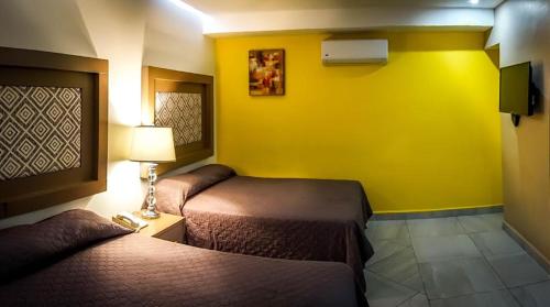 a hotel room with two beds and a yellow wall at JM Express in Monterrey