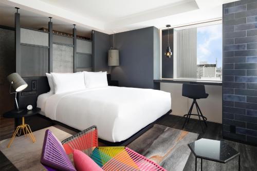 a bedroom with a large white bed and chairs at Aloft Tokyo Ginza in Tokyo