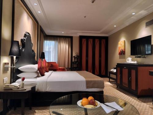 una habitación de hotel con una cama y una mesa con un bol de fruta en St. Mark's Hotel en Bangalore
