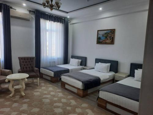 a room with three beds and a chair and a table at GRAND SARBON HOTEL in Qarshi
