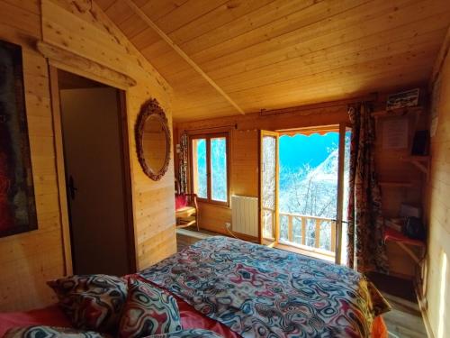 Un dormitorio con una cama y una ventana grande. en Les Toits Rouges le luxe de la simplicité, en Saint-Étienne-de-Tinée