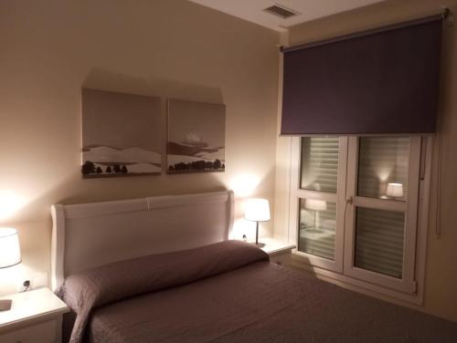 een slaapkamer met een bed met 2 ramen en 2 lampen bij Áncora apartamento in El Puerto de Santa María